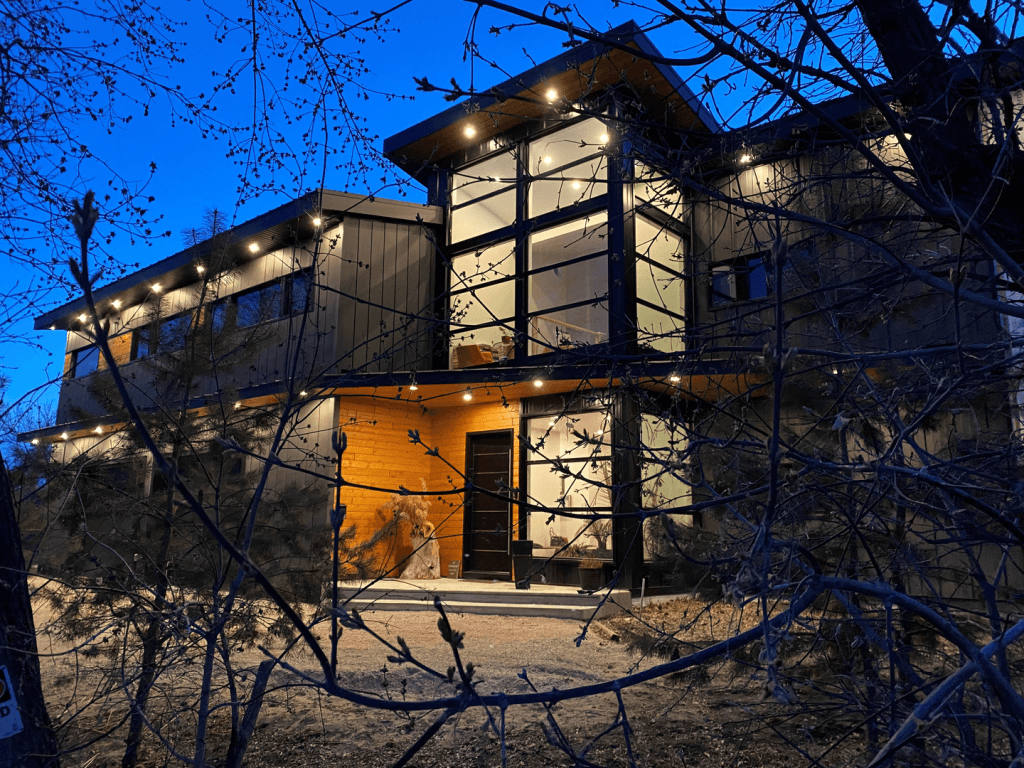 Stylish two-story building with a mix of wood and metal siding, showcasing large windows and a wooden door.