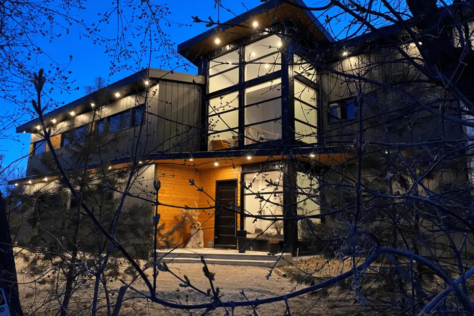 Stylish two-story building with a mix of wood and metal siding, showcasing large windows and a wooden door.