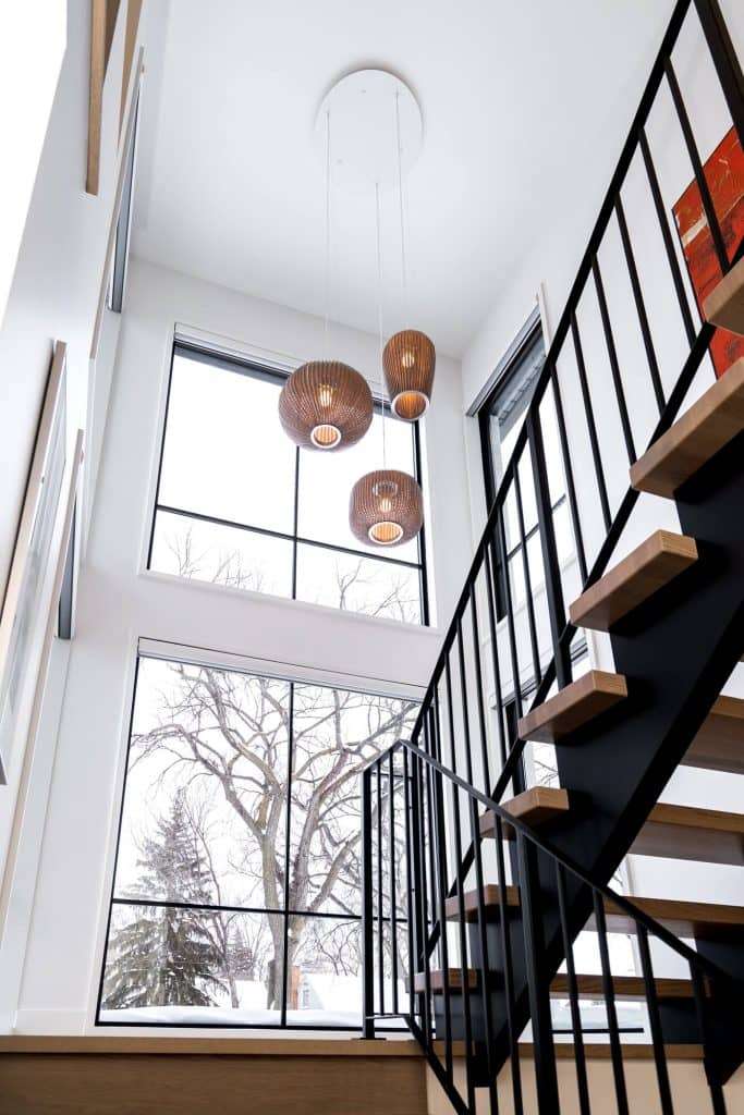 Bright interior with a floating staircase and large picture windows, providing a seamless connection between indoor spaces and the snowy outdoor landscape.