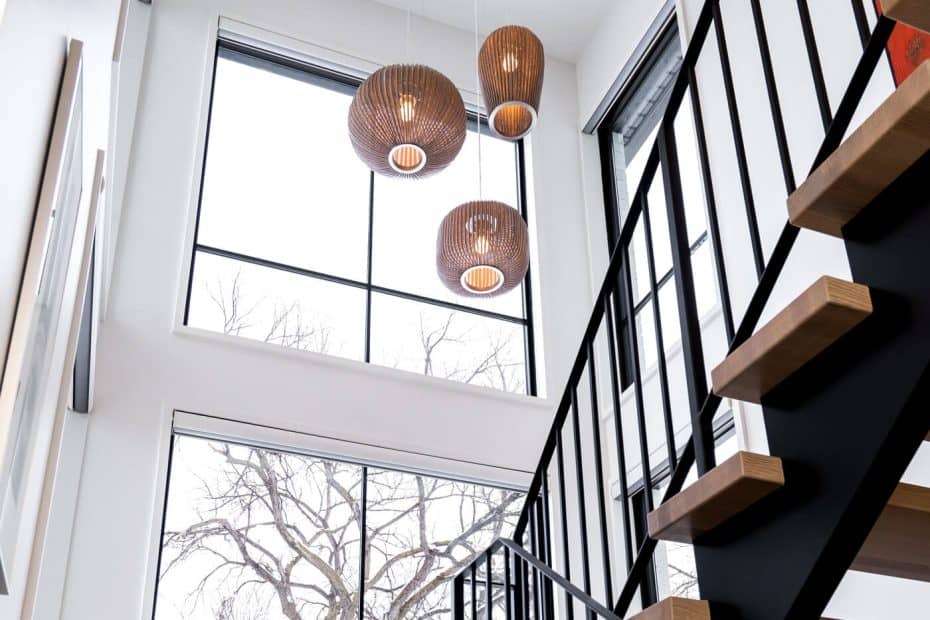 Bright interior with a floating staircase and large picture windows, providing a seamless connection between indoor spaces and the snowy outdoor landscape.